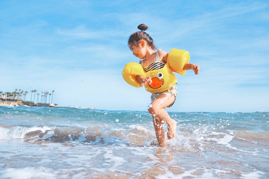 little girl playing in surf on tropical beach