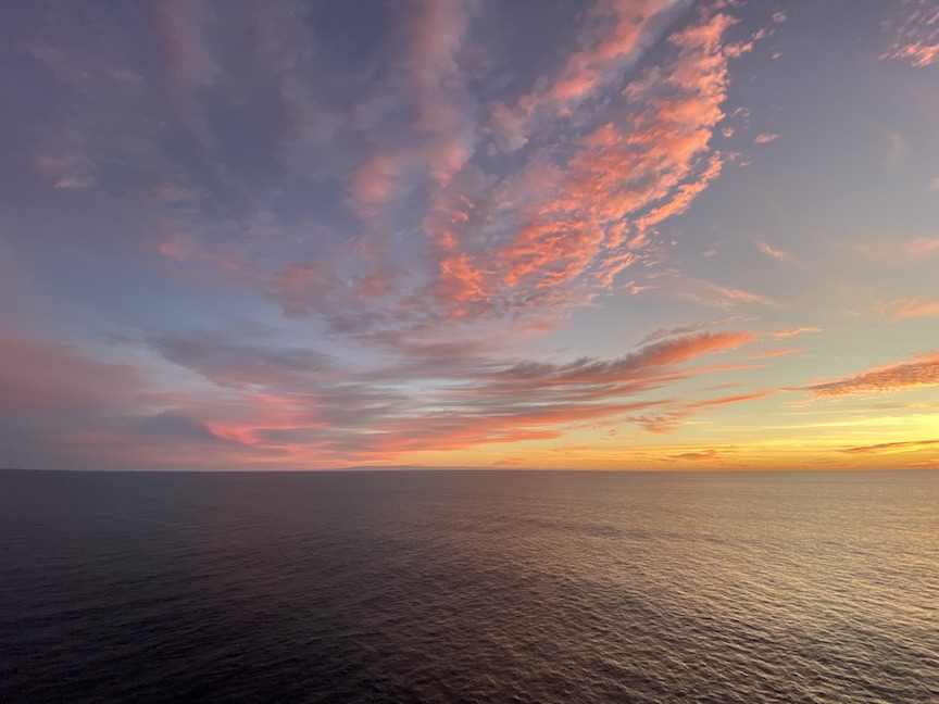 cruise photo ideas - photo of a dramatic sunrise with pink clouds, orange horizon, and calm sea