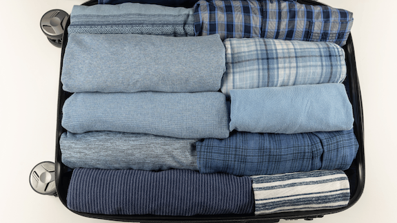packing light for a long cruise - open suitcase with rolled shirts and pants