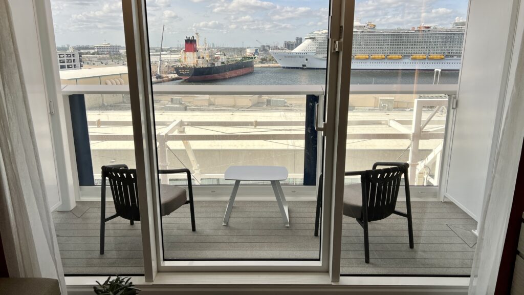 The spacious balcony on the Ascent Sky Suite with two cushioned armchairs, a small white table, and a fabulous view.