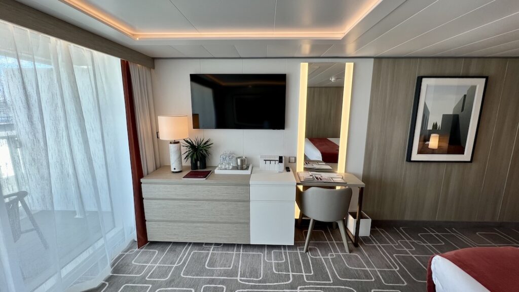 Functional desk area, refreshment center, and concealed mini-fridge in Celebrity Ascent Sky Suite, blending convenience with style.