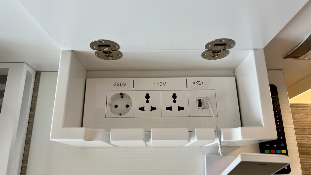 Interior of a white wooden box that has one 220V outlet, two 110V outlets, and two USB plugs.