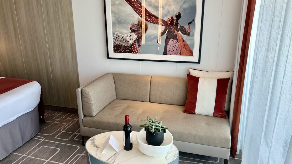 Comfortable seating in the Ascent Sky Suite, provided by a one-arm sofa with throw pillows. In front is an oval marble-topped coffee table.